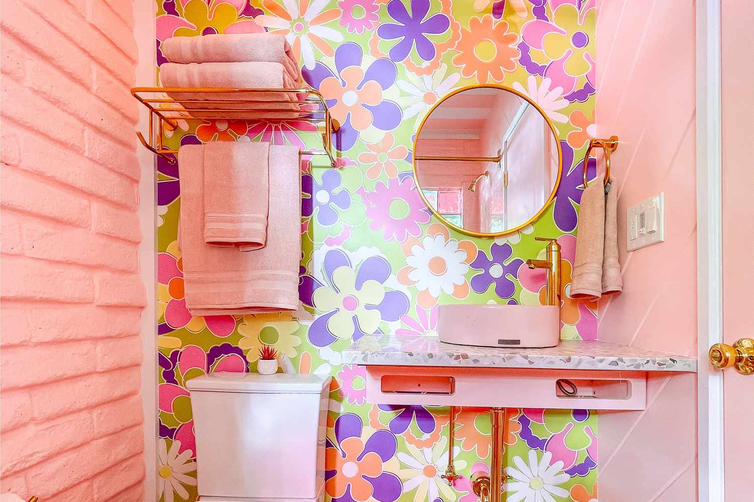 Salle de bain rose avec papier peint imprimé marguerite.