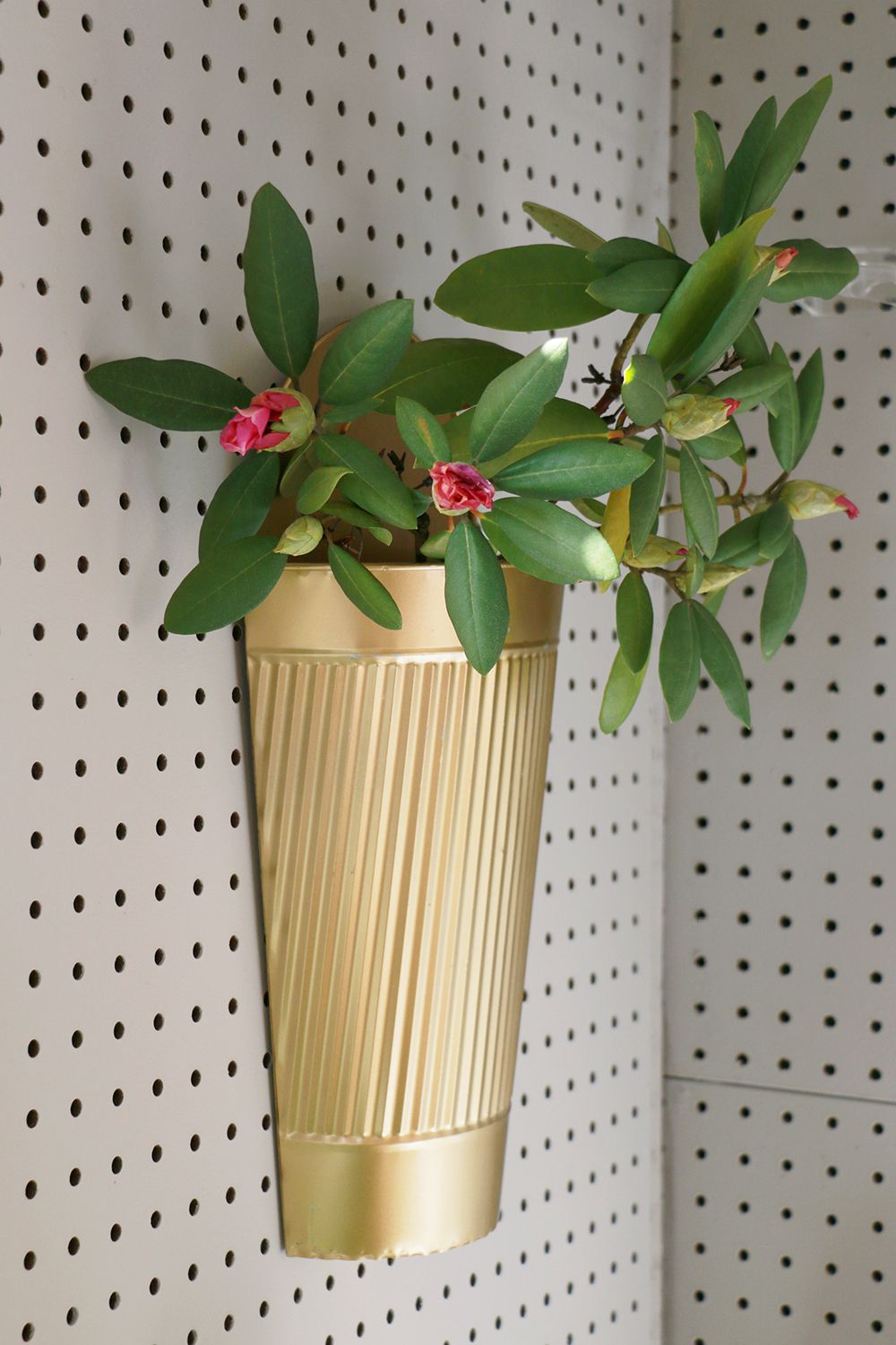 Jardinière avec des fleurs fixée à un mur de panneaux dans une remise.