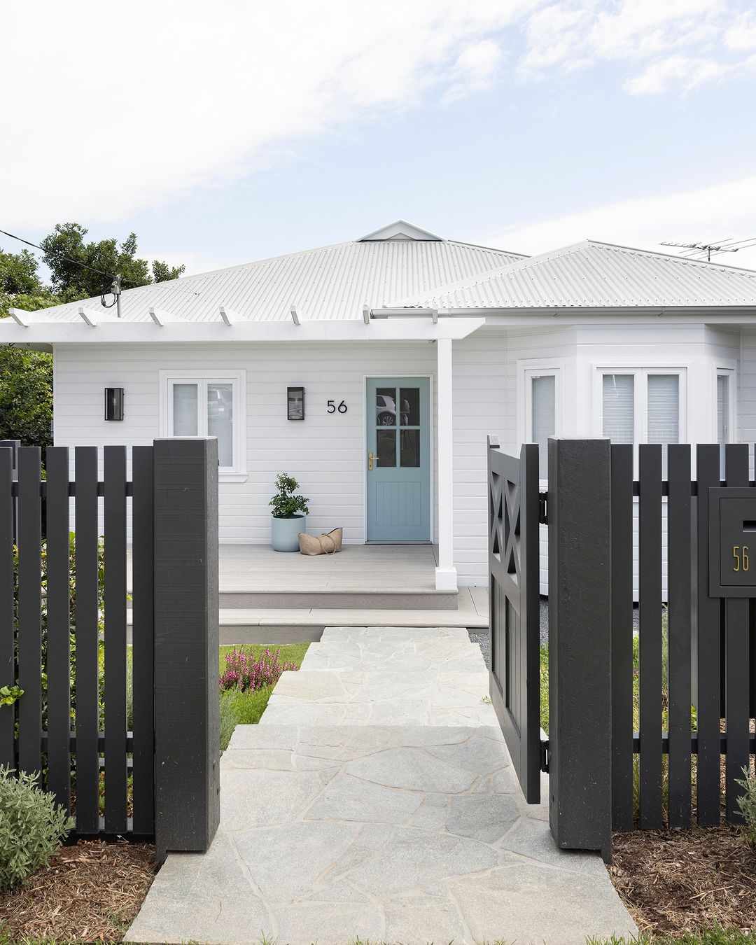 Maison blanche avec porte bleu clair et clôture noire