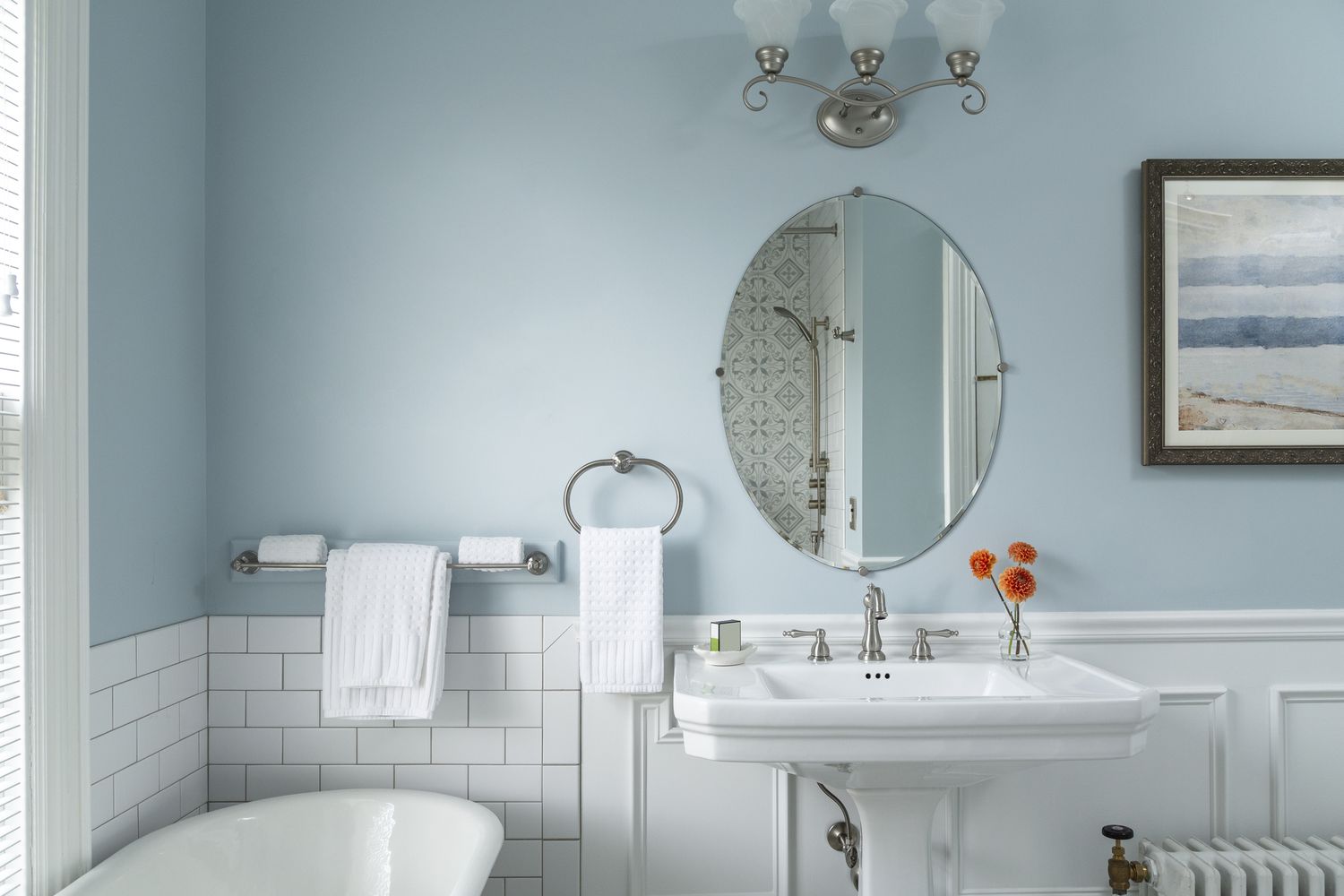 Baignoire et meuble-lavabo dans une salle de bains lumineuse aux murs peints en bleu pâle.