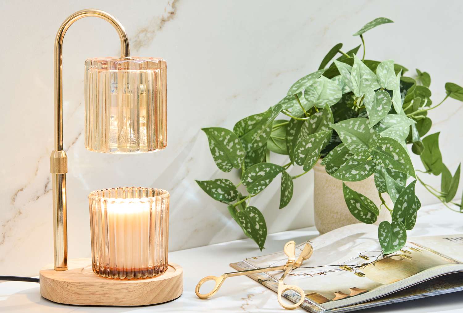 Un chauffe-bougie sur une surface en marbre avec une plante pothos.