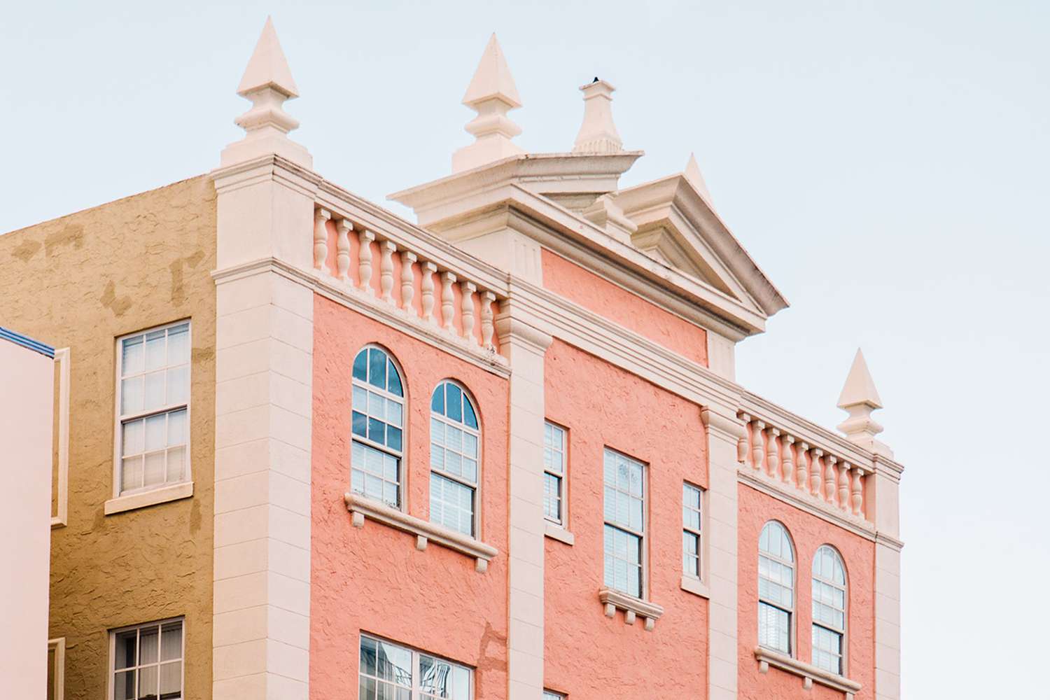 Bâtiment de couleur rose et saumon avec des fenêtres et des parapets de style art déco.
