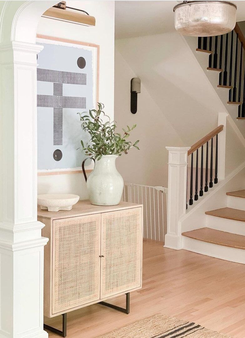 Entrée avec armoire en rotin, applique en laiton et peinture neutre