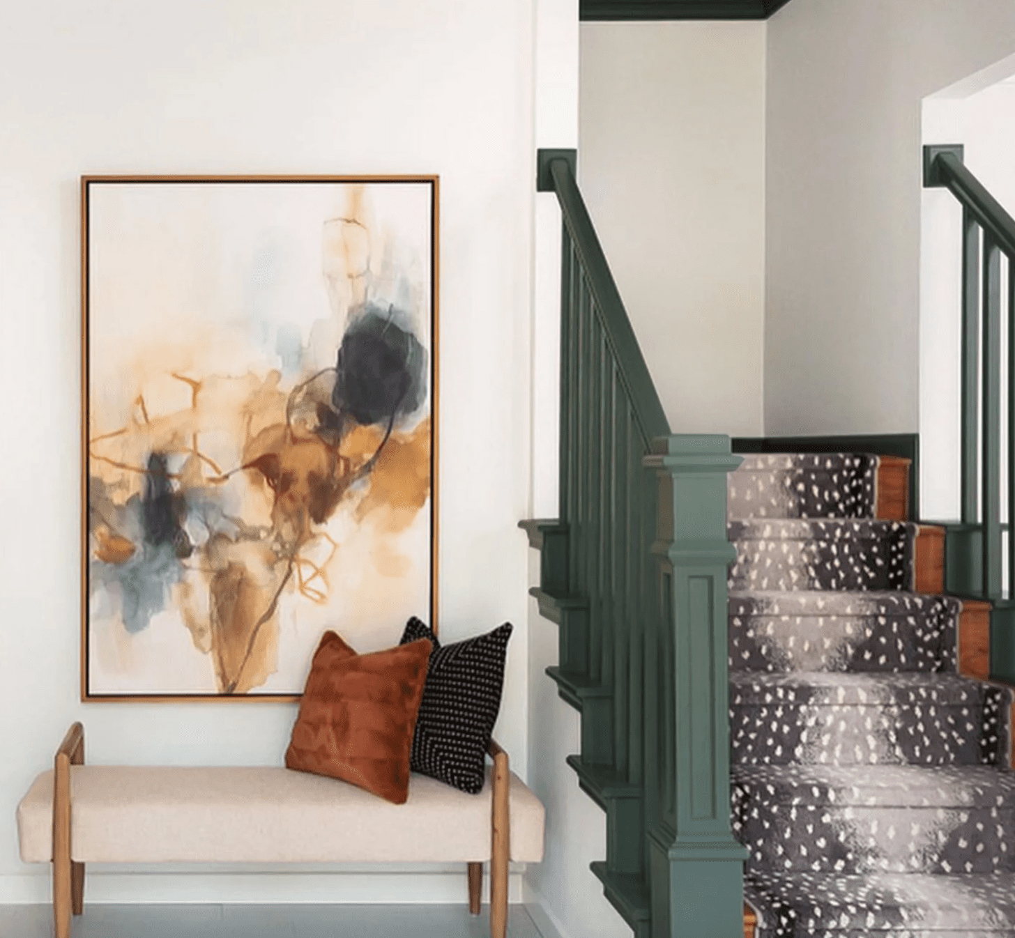 Entrée avec escalier peint en vert foncé, marches en moquette grise et banc blanc neutre