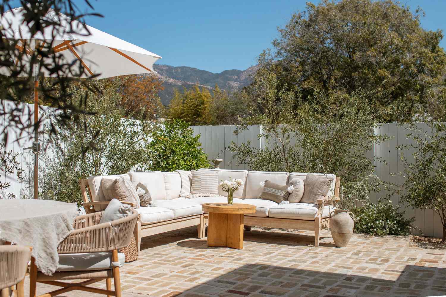 Jardin méditerranéen californien avec canapé d'extérieur blanc adossé à des oliviers
