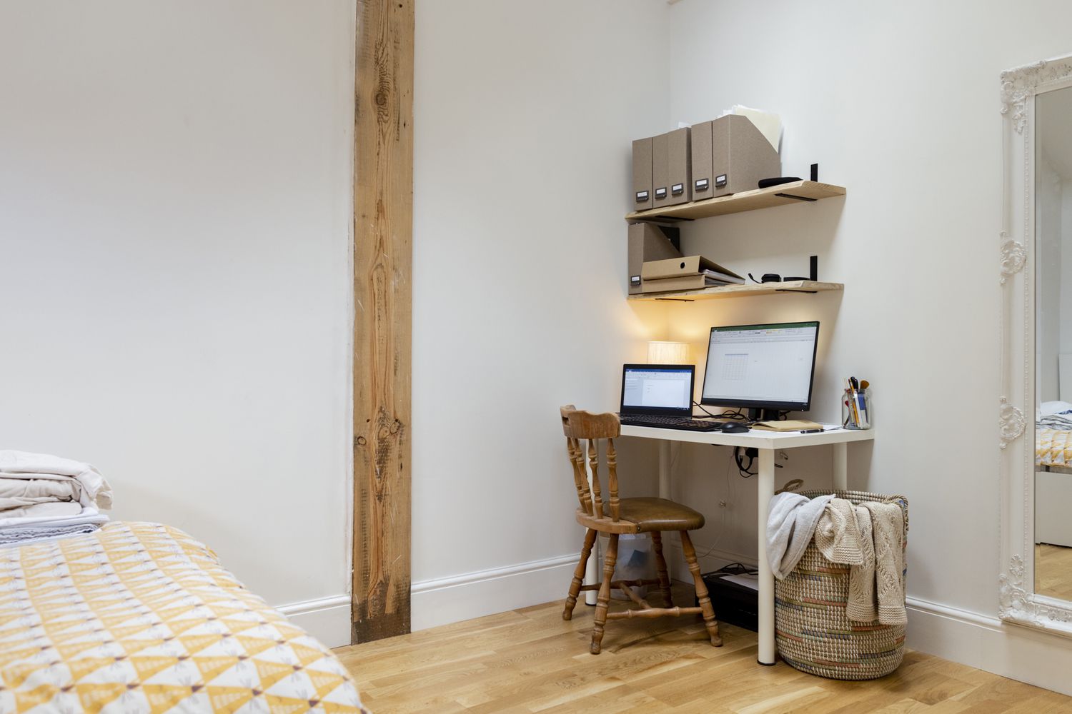 Bureau dans une chambre avec ordinateur portable et moniteur et panier à linge