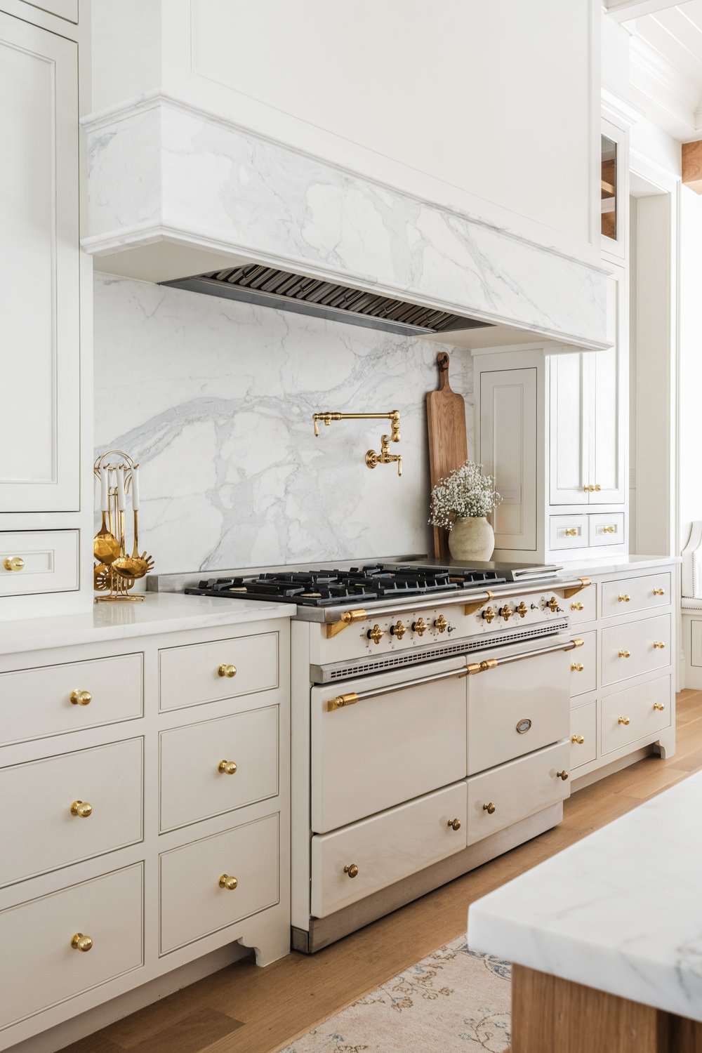 Cuisine blanche élégante avec des boutons d'armoire dorés.