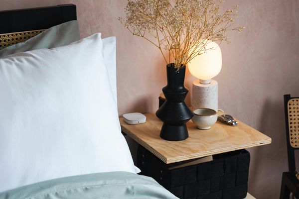 Lit avec lampe et vase sur table de chevet