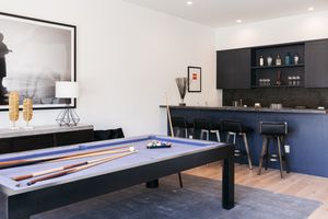 Basement room with white painted walls with purple pool table and black decor bar