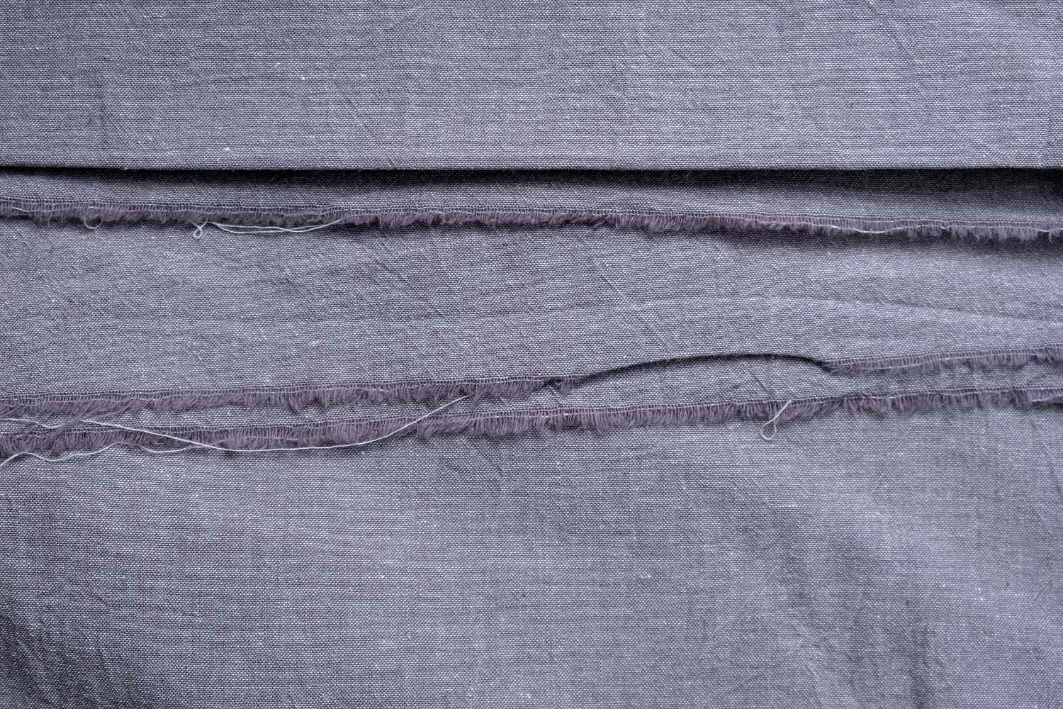Coutures déchirées sur un tissu en lin.