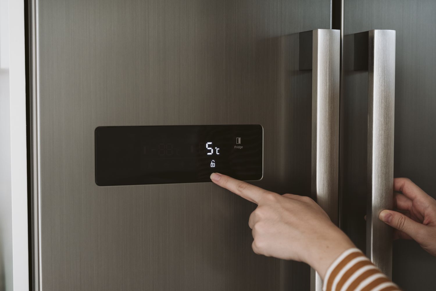 Close-up of woman adjusting cooling temperature at fridge