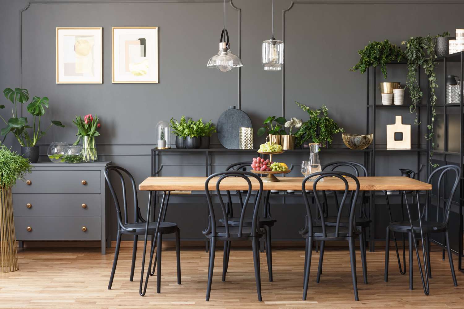 Dining room with dark gray walls with picture frame molding and modern furnishings, decor, and lighting