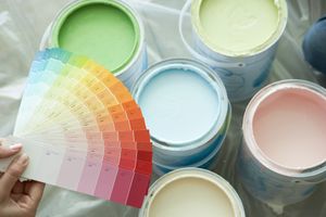 Mains tenant des échantillons de peinture au-dessus de pots de peinture ouverts