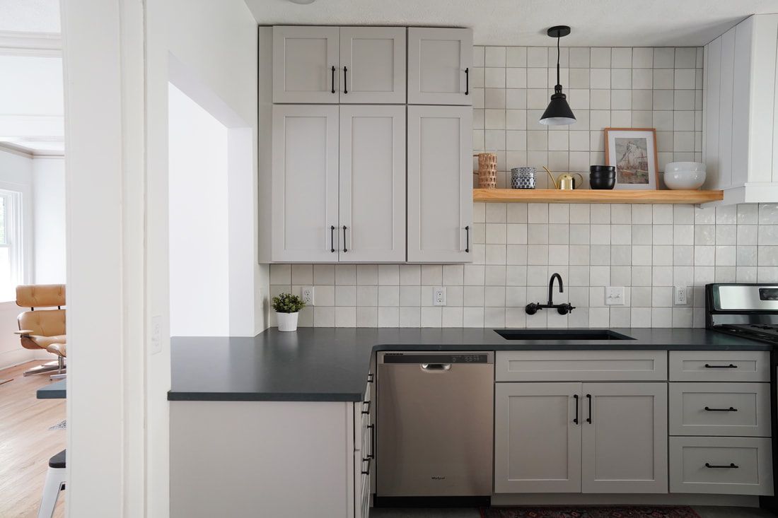 A kitchen with soft gray cabinets and black granite countertop