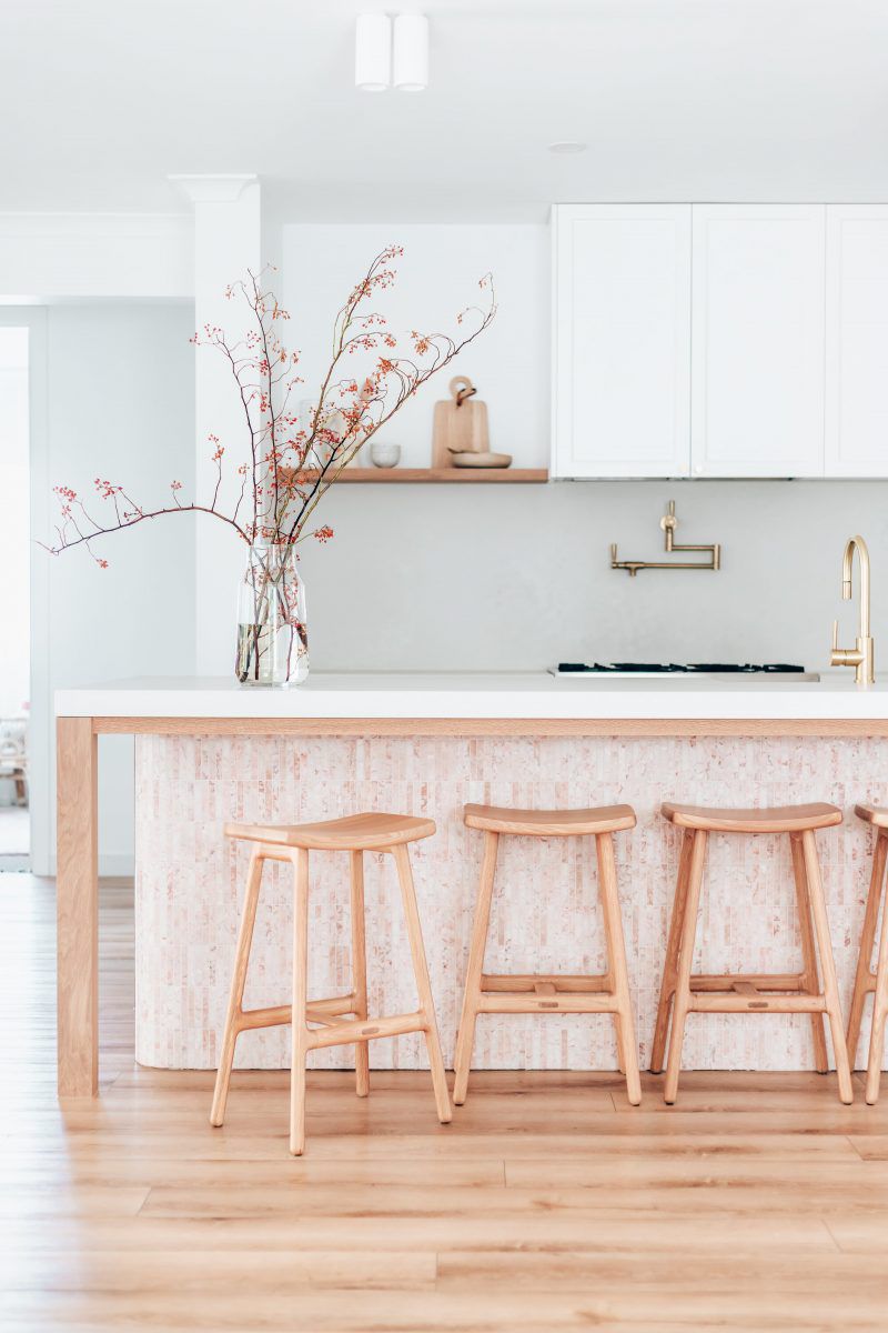 A kitchen with white cabinets and a pink tile island