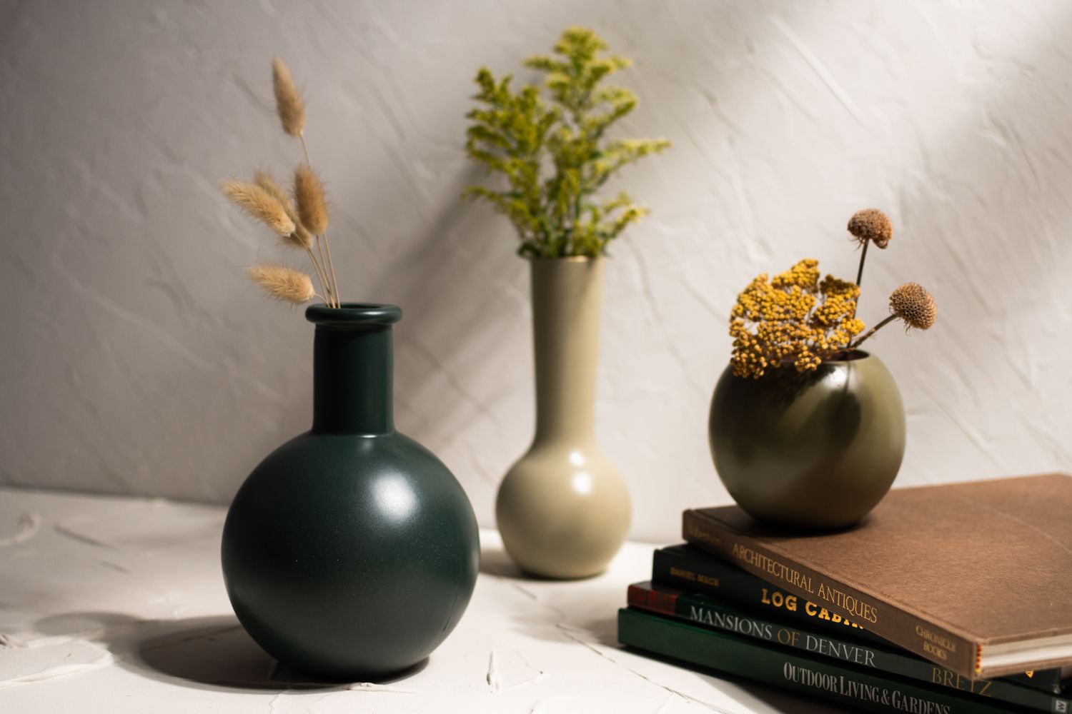 Painted glass vases with small flower bundles stacked on books